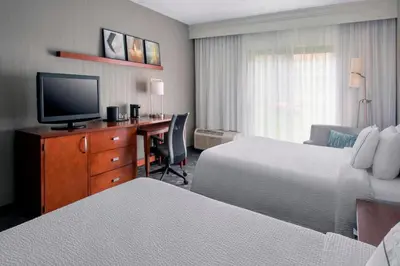 a hotel room with two beds and a desk with a television at Courtyard Newark Liberty International Airport in Newark