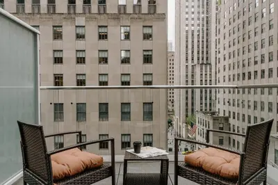 a balcony with two chairs and a table and a building at The Jewel Hotel, New York in New York