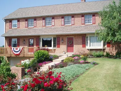 a red brick house with flowers in the yard at Homestead Lodging in Smoketown