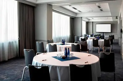 a conference room with tables and chairs and a screen at Philadelphia Airport Marriott in Philadelphia