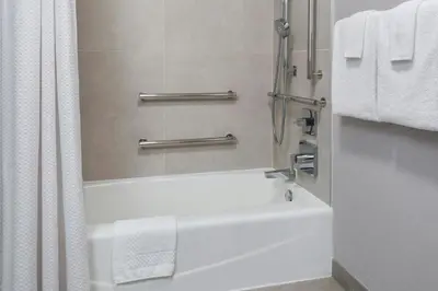a bathroom with a tub and a shower with towels at Courtyard By Marriott Jersey City Newport in Jersey City