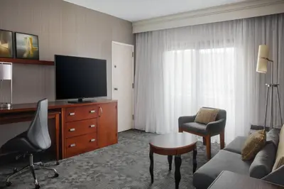 a hotel room with a television and a living room at Courtyard Philadelphia Devon/Villanova in Wayne