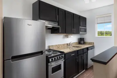a kitchen with a stainless steel refrigerator and black cabinets at MainStay Suites Mt Laurel - Philadelphia in Mount Laurel