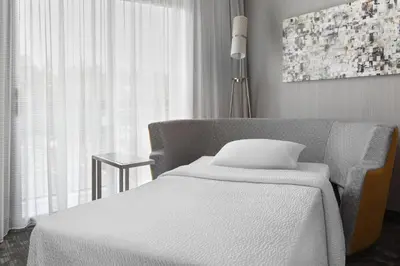 a bedroom with a bed and a chair and a window at Courtyard Philadelphia Willow Grove in Willow Grove