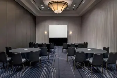 a conference room with tables and chairs and a screen at Marriott Philadelphia West in West Conshohocken