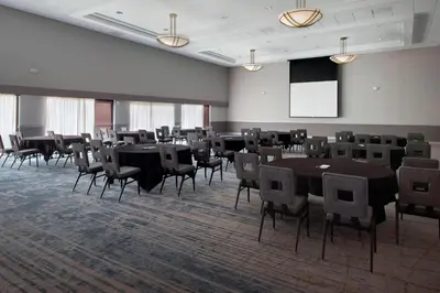 a conference room with tables and chairs and a screen at Princeton Marriott at Forrestal in Princeton