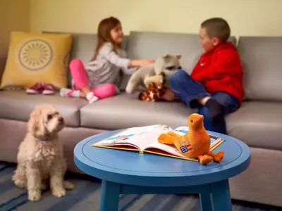a boy and a girl sitting on a couch with a table and a dog at Sonesta ES Suites Allentown Bethlehem Airport in Bethlehem