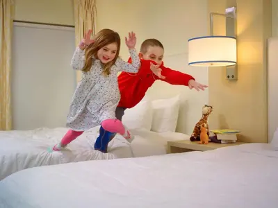 a boy and a girl jumping on a bed at Sonesta ES Suites Allentown Bethlehem Airport in Bethlehem
