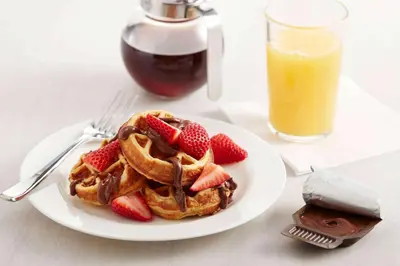 a plate of waffles with strawberries and a glass of orange juice at Sonesta ES Suites Allentown Bethlehem Airport in Bethlehem