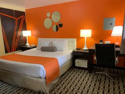 a hotel room with a bed with an orange wall at Howard Johnson by Wyndham North Bergen in North Bergen
