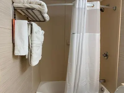 a bathroom with a white shower curtain and towels at Howard Johnson by Wyndham North Bergen in North Bergen