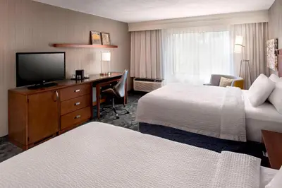a hotel room with two beds and a desk with a television at Courtyard Parsippany in Parsippany