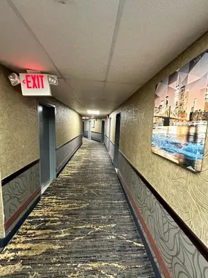 a hallway in a building with an exit sign on the wall at Town House Inn and Suites in Elmwood Park