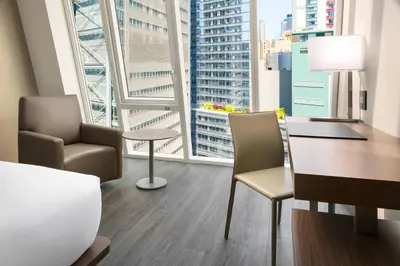 a hotel room with a desk and chairs and a large window at AC Hotel by Marriott New York Times Square in New York