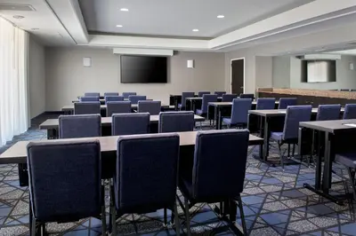 a conference room with tables and chairs and a screen at Courtyard Philadelphia Plymouth Meeting in Plymouth Meeting