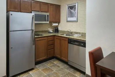 a kitchen with wooden cabinets and a stainless steel refrigerator at Residence Inn Cranbury South Brunswick in Cranbury