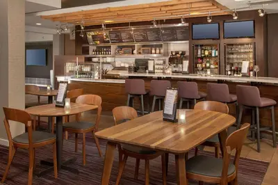 a restaurant with wooden tables and chairs and a bar at Sonesta Select Newark Christiana Mall in Newark