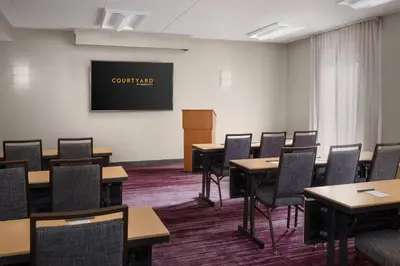 a conference room with tables and chairs and a screen at Courtyard Philadelphia Valley Forge / King of Prussia in Wayne