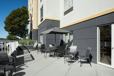 a patio with chairs and tables and an umbrella at Fairfield Inn & Suites by Marriott Newark Liberty International Airport in Newark