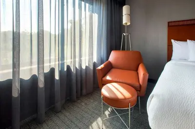 a bedroom with a bed and a chair next to a window at Courtyard by Marriott Paramus in Paramus