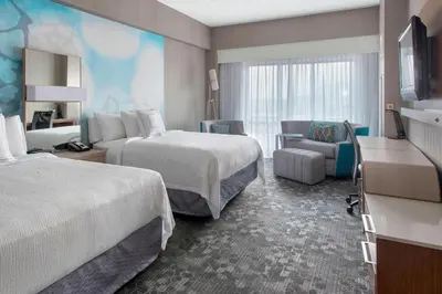 a hotel room with two beds and a couch at Courtyard by Marriott Newark Elizabeth in Elizabeth