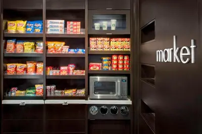 a kitchen with a microwave and a shelf with food at Courtyard by Marriott Newark Elizabeth in Elizabeth
