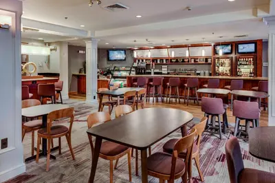 a restaurant with tables and chairs and a bar at Courtyard by Marriot Cranbury South Brunswick in Cranbury