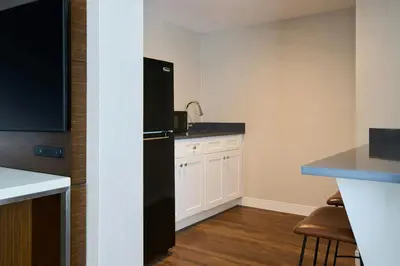 a kitchen with a black refrigerator and white cabinets at Renaissance Meadowlands Hotel in Rutherford