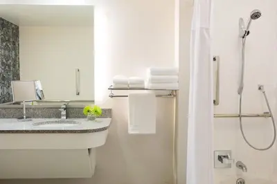 a bathroom with a sink and a shower with towels at Renaissance Meadowlands Hotel in Rutherford