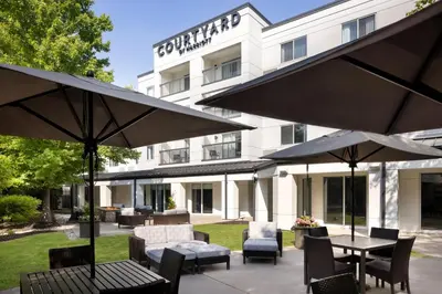 a patio with tables and umbrellas in front of a hotel at Courtyard Edison Woodbridge in Edison