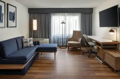 a living room with a blue couch and a desk at Courtyard Edison Woodbridge in Edison