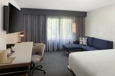 a hotel room with a bed and a couch at Courtyard Edison Woodbridge in Edison