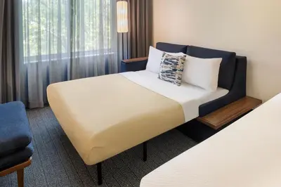 a hotel room with a bed and a chair at Courtyard Edison Woodbridge in Edison