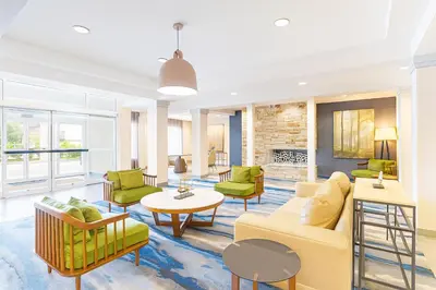 a living room with yellow furniture and green chairs at Fairfield Inn & Suites by Marriott Edison - South Plainfield in Edison