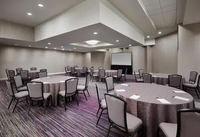a conference room with tables and chairs and a screen at Hanover Marriott in Whippany