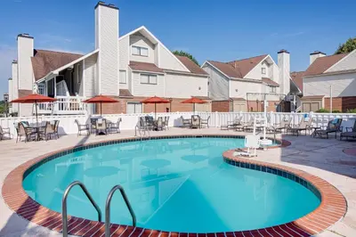 a swimming pool at a resort with chairs and umbrellas at Residence Inn by Marriott Harrisburg Hershey in Harrisburg