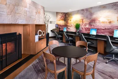 a waiting room with a fireplace and a table and chairs at Courtyard Bethlehem Lehigh Valley/I-78 in Bethlehem
