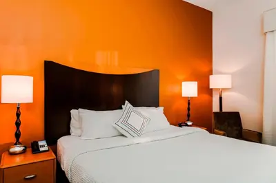 a bedroom with a large bed with an orange wall at Fairfield by Marriott Wilkes-Barre in Wilkes-Barre