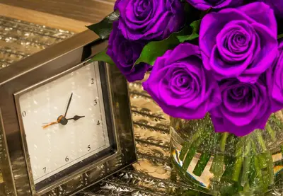 a vase filled with purple roses next to a clock at Four Seasons Hotel New York in New York
