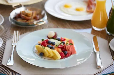 a plate of fruit on a table with a meal at Four Seasons Hotel New York in New York