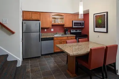 a kitchen with a refrigerator and a table with chairs at Residence Inn Binghamton in Vestal