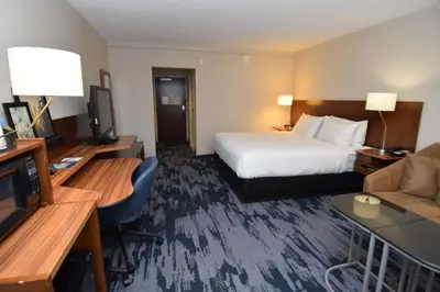 a hotel room with a bed and a couch and a television at Fairfield Inn by Marriot Binghamton in Binghamton