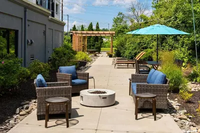a patio with chairs and an umbrella and a fire pit at Courtyard Binghamton in Vestal