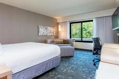 a hotel room with a bed and a couch and a desk at Courtyard Binghamton in Vestal