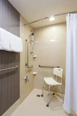 a shower with a white chair in a bathroom at Courtyard Binghamton in Vestal