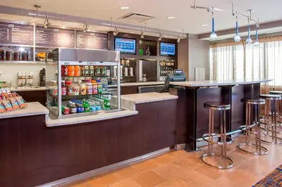 a bar in a restaurant with a refrigerator and stools at Courtyard Binghamton in Vestal