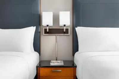two beds with white pillows and a table between them at Courtyard Montvale in Montvale