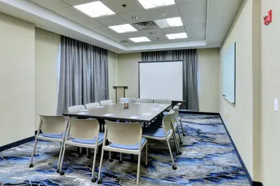 a conference room with a table and chairs and a whiteboard at Fairfield Inn & Suites Woodbridge in Avenel