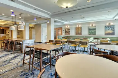 a restaurant with tables and chairs and a bar at Fairfield Inn & Suites Woodbridge in Avenel
