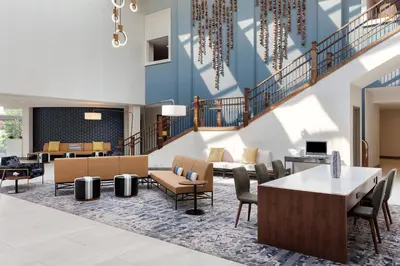 a lobby with chairs and tables and a staircase at Delta Hotels by Marriott Woodbridge in Iselin